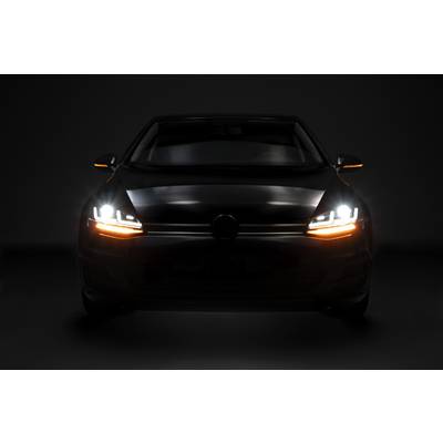 A car head-on in darkness with dipped headlights switched on and indicators flashing orange and white.