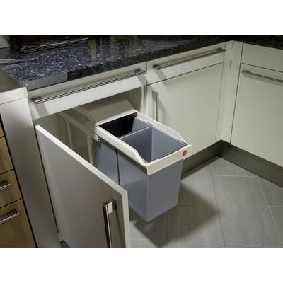An open kitchen drawer with a pull-out waste bin beneath the worktop, revealing a grey rubbish bin.