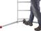 A person wearing jeans and boots steps onto a ladder base with a red, non-slip foot. Safety in ladder use is demonstrated.