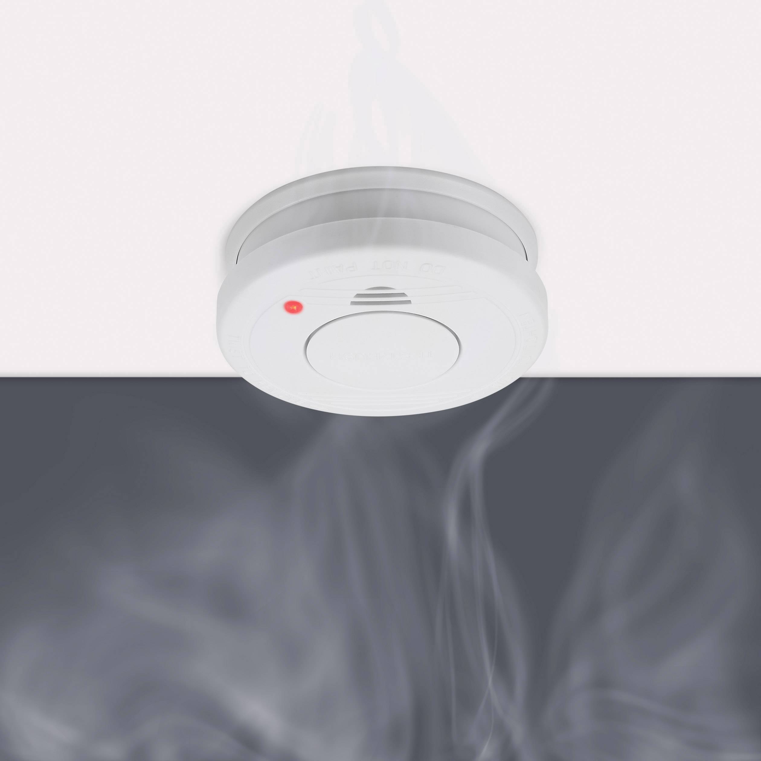 A smoke detector on the ceiling activates a red LED and emits a warning signal as smoke rises.