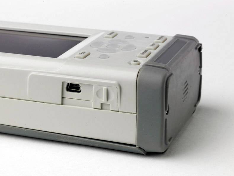 A portable electronic device with keys and a screen. On the side, there is a USB port.