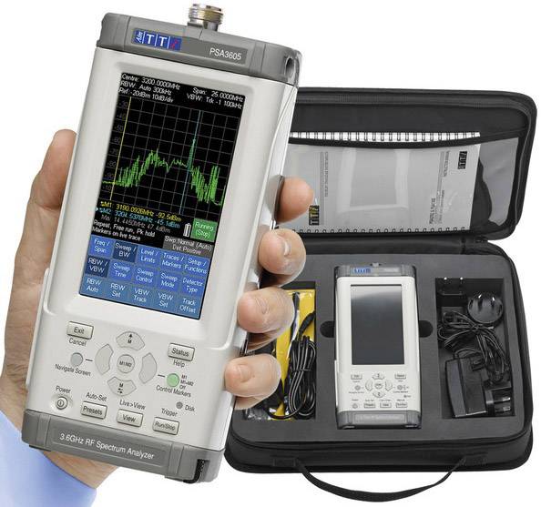 Portable 3 GHz RF spectrum analyser with accessories in a black carrying case. Display shows frequency analyses. Includes charger and cables.
