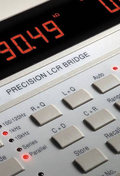 A precision LCR measuring device with a digital display is showing a measurement value. Details of button labels and configuration options are visible.