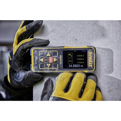 A device for measuring distance is held by gloved hands against a concrete surface. It displays a distance of 34.886 metres.