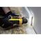 A person is using a yellow electric tool to make precise cuts on a skirting board on a wooden platform.