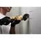 A man is cutting holes in a plasterboard wall using a rotary tool. He is wearing work gloves.