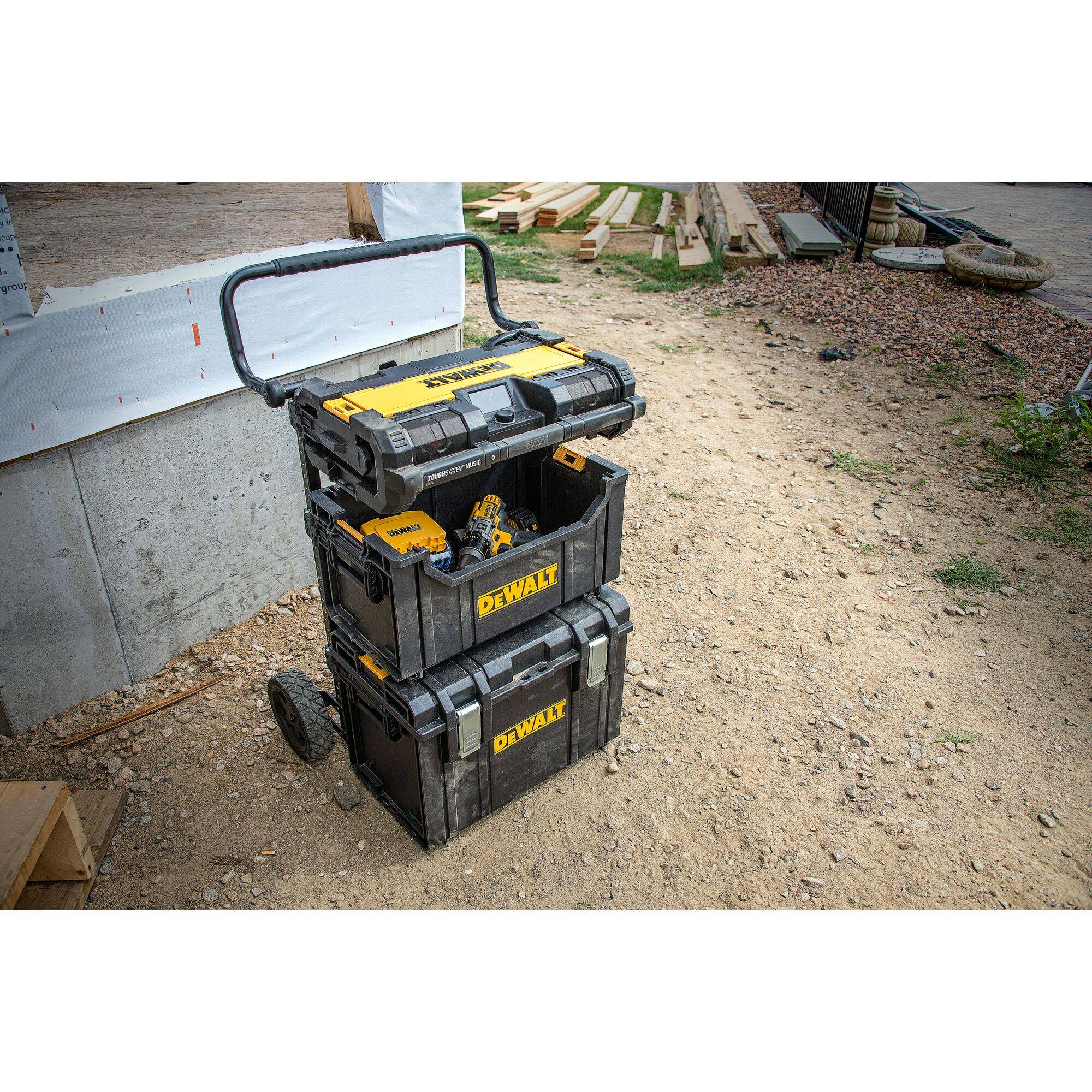 'A stackable toolbox on wheels in front of a construction site. The boxes are yellow and black and branded with the manufacturer's name.'