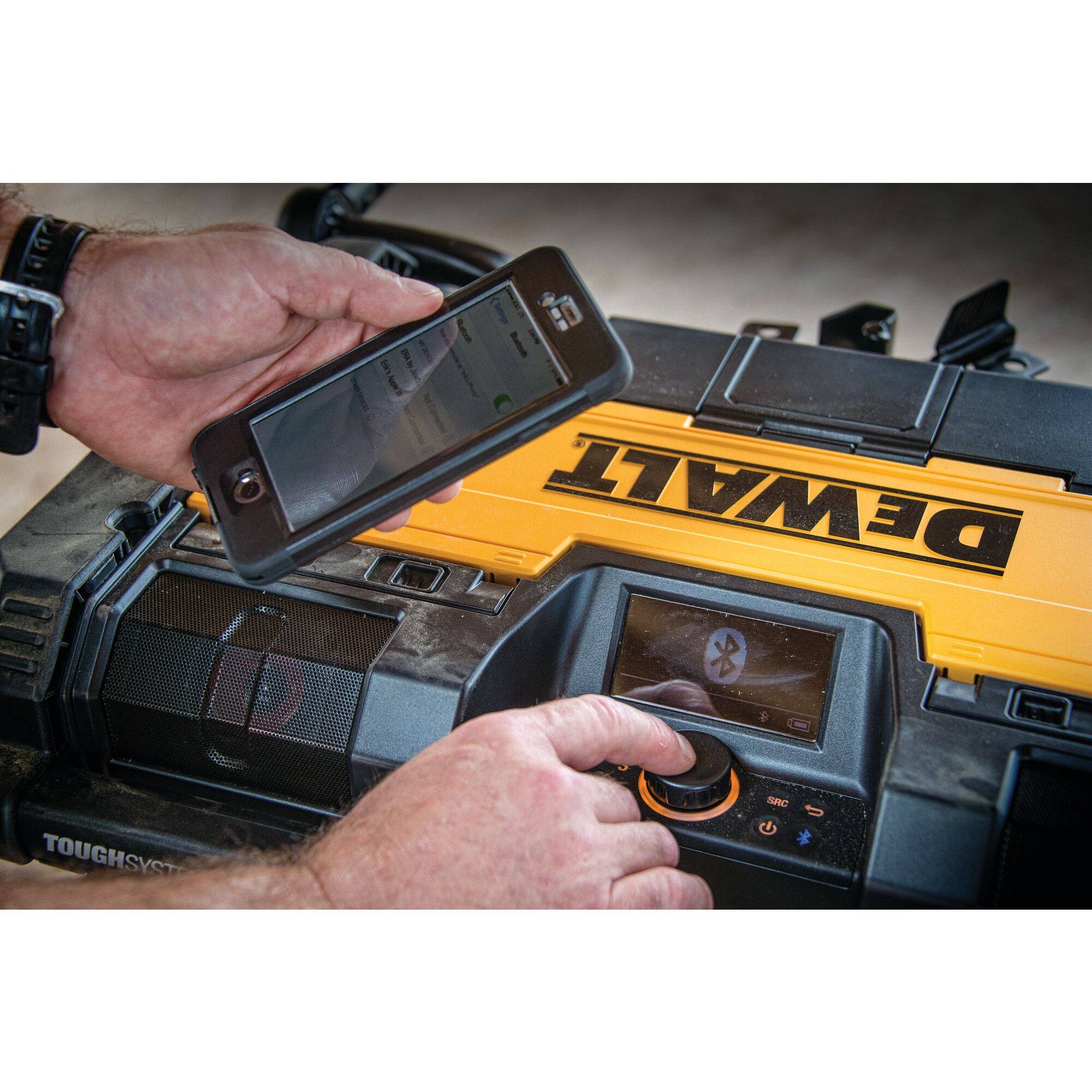 A person connects a smartphone via Bluetooth to a DeWalt device. The device has a display and controls.