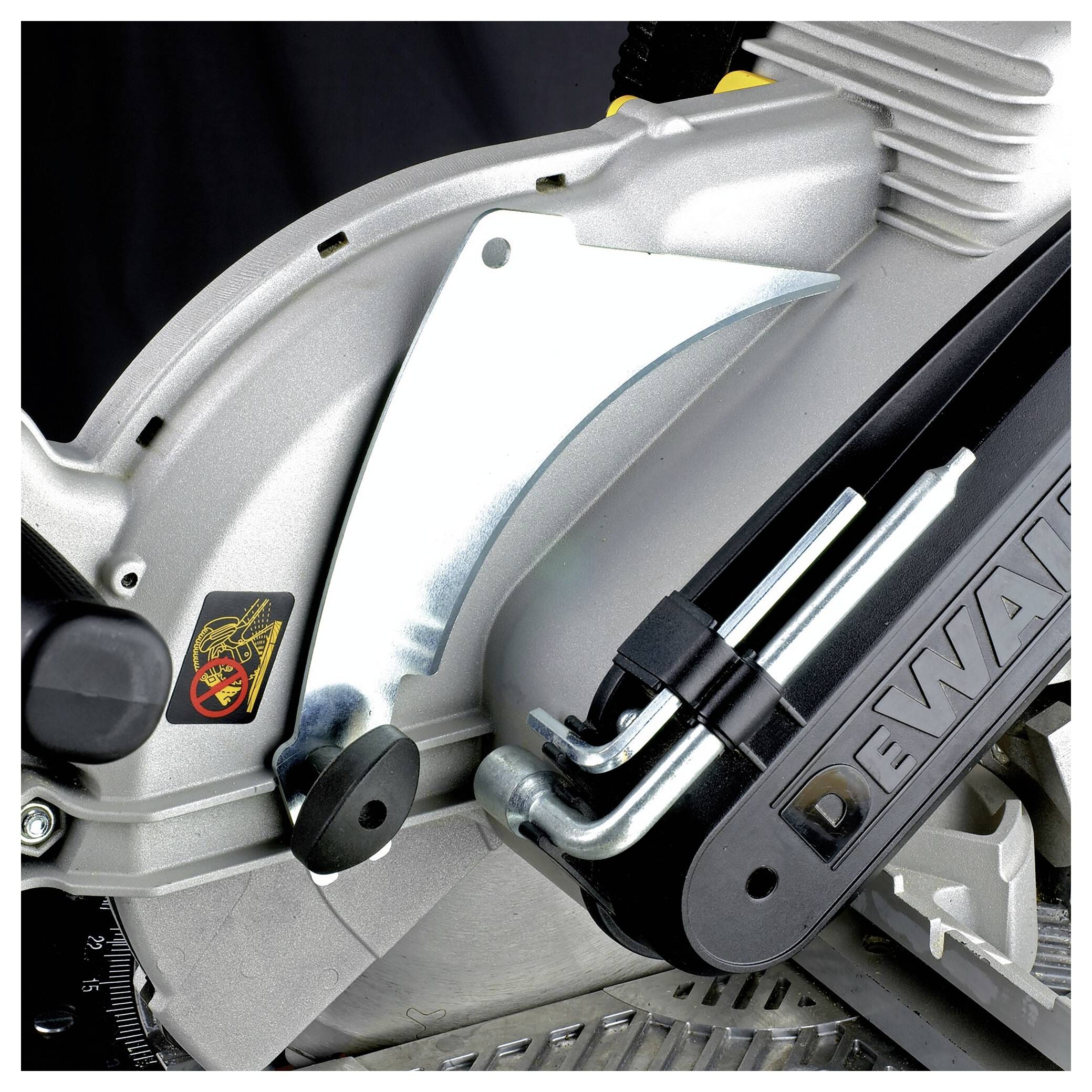 A close-up of part of an electric circular saw with a trademark. A silver protective guard and a spanner holder are visible.