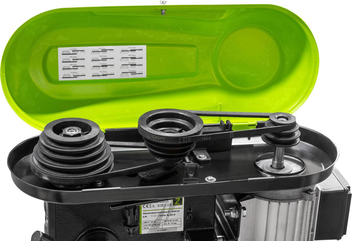 An open machine drive reveals several pulleys and belts beneath a green cover, with a diagram sticker inside.