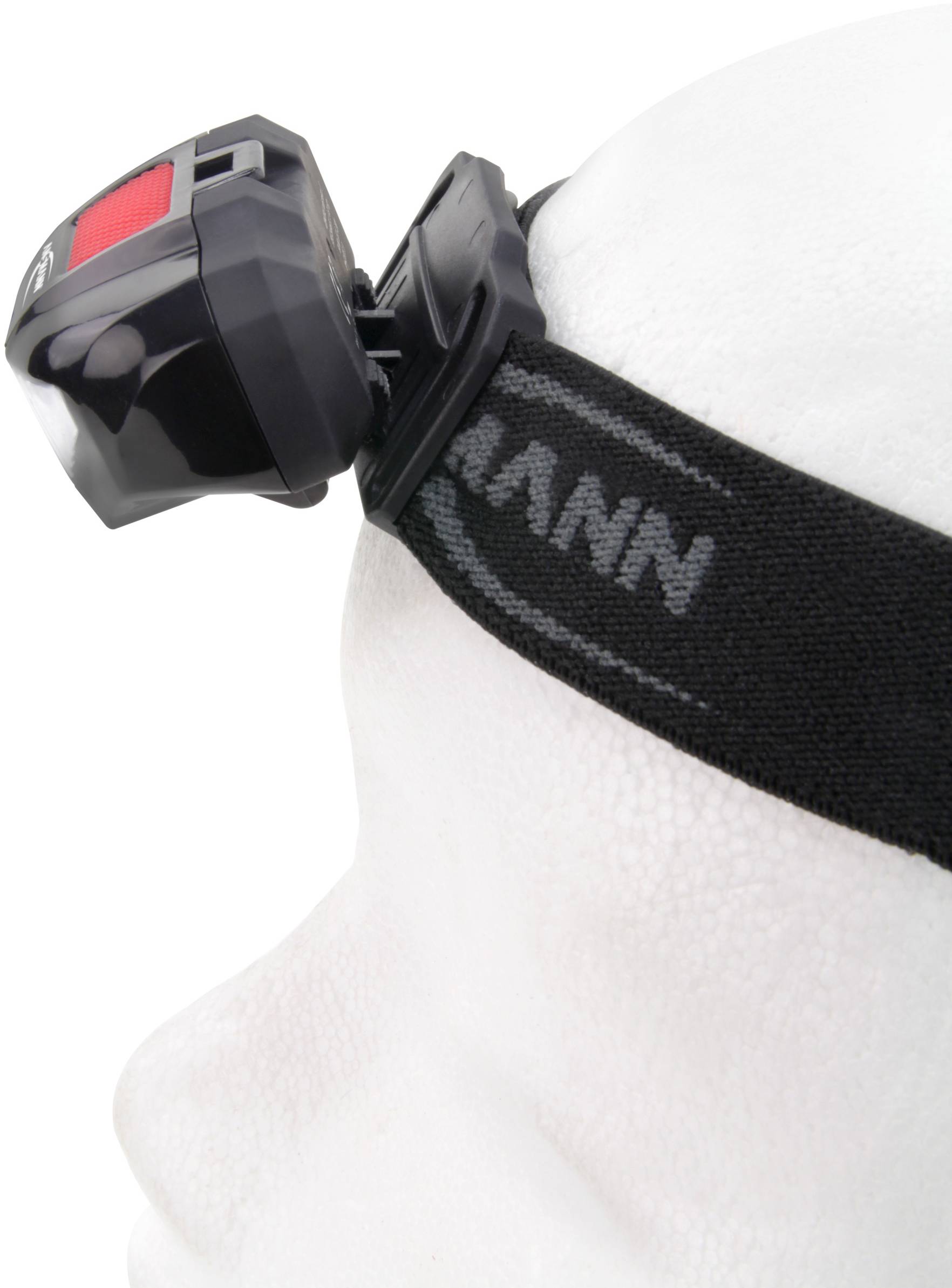 Person wearing a head torch, mounted on a black elastic band, viewed from the side.