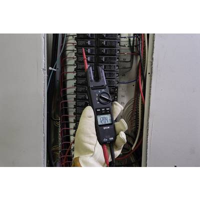 A person is measuring the voltage in an electrical cabinet with a multimeter, displayed value: 120.4 V. They are wearing safety gloves.
