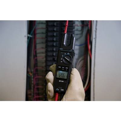 A person is holding a multimeter against an electrical control cabinet and measuring 120.6 volts. Red and black cables are being used.