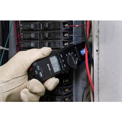 A person wearing protective gloves is measuring the current flow at an electrical control cabinet using a digital multimeter.