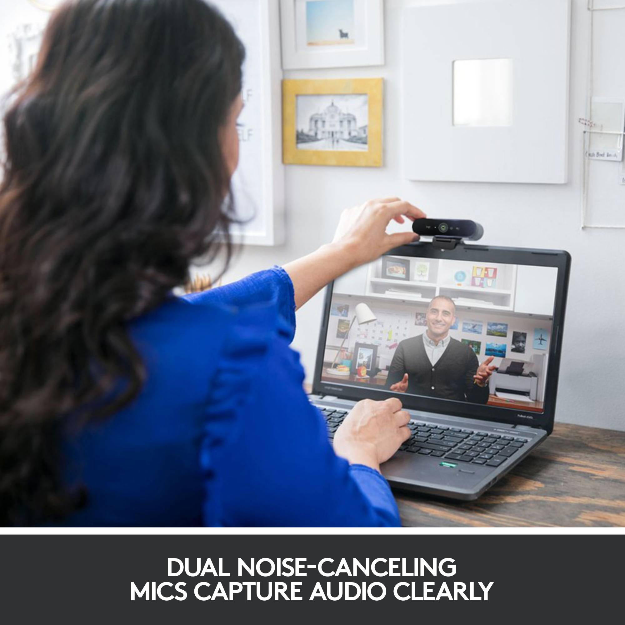 A person is on a video call on a laptop, while another person adjusts the camera above the screen.