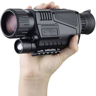 A hand holds a night vision device with lens and eyepiece. The device is black and compact, suitable for nocturnal observations.