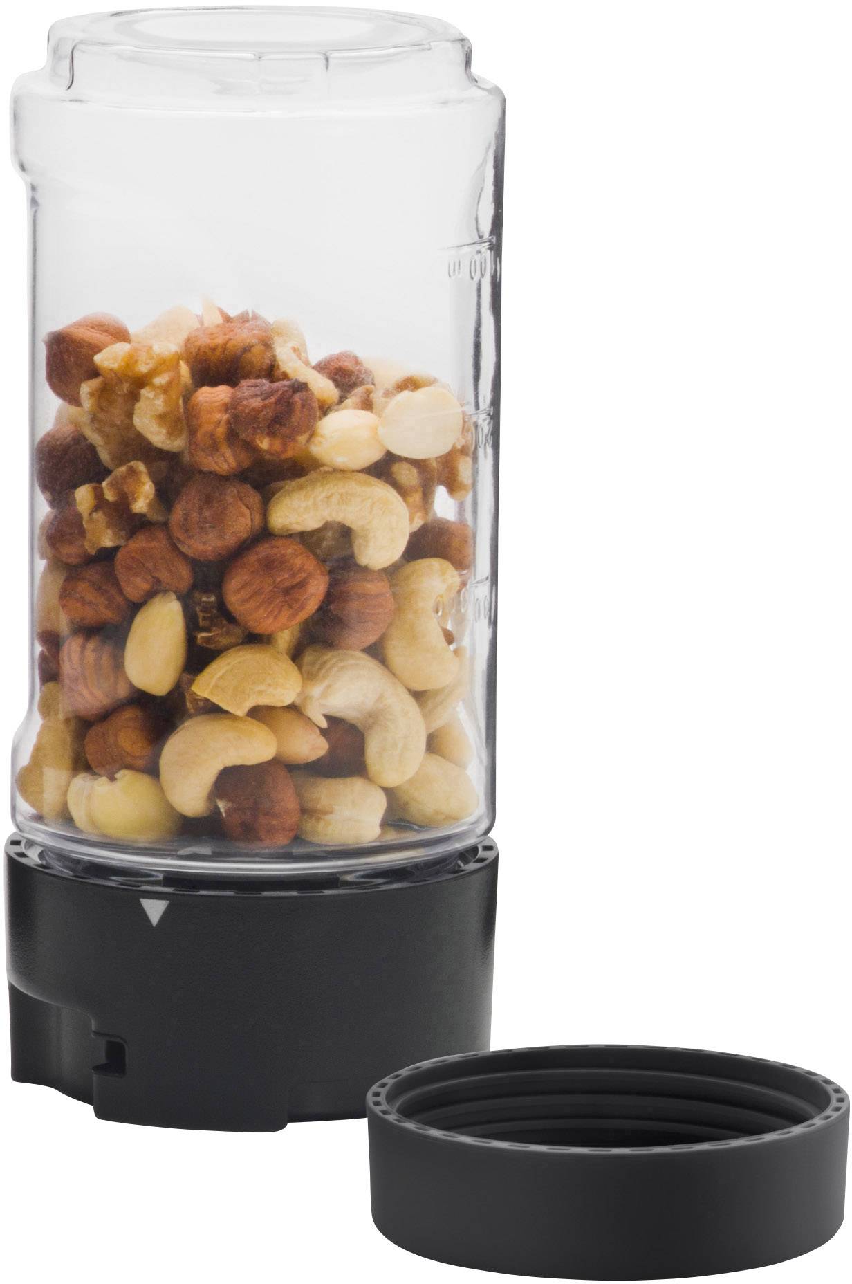 A transparent jar containing a mixture of hazelnuts and cashew nuts, with a removable black lid placed beside it.