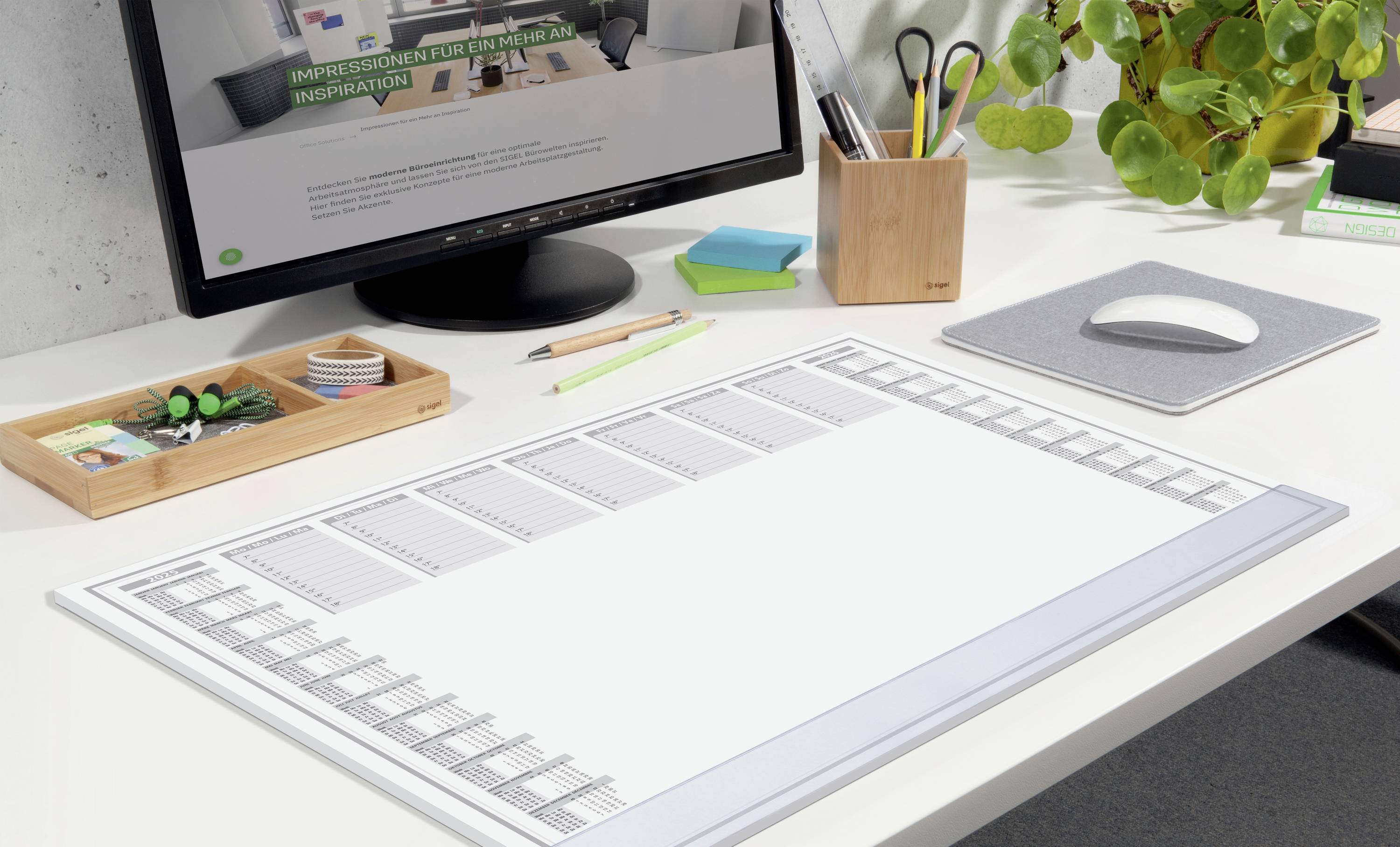 A desk with a large, white writing pad. A computer screen displaying a website is in the background. Office supplies are at the ready.