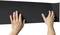 Two hands are holding a black, rectangular material with a textured surface, likely a mat or panel.