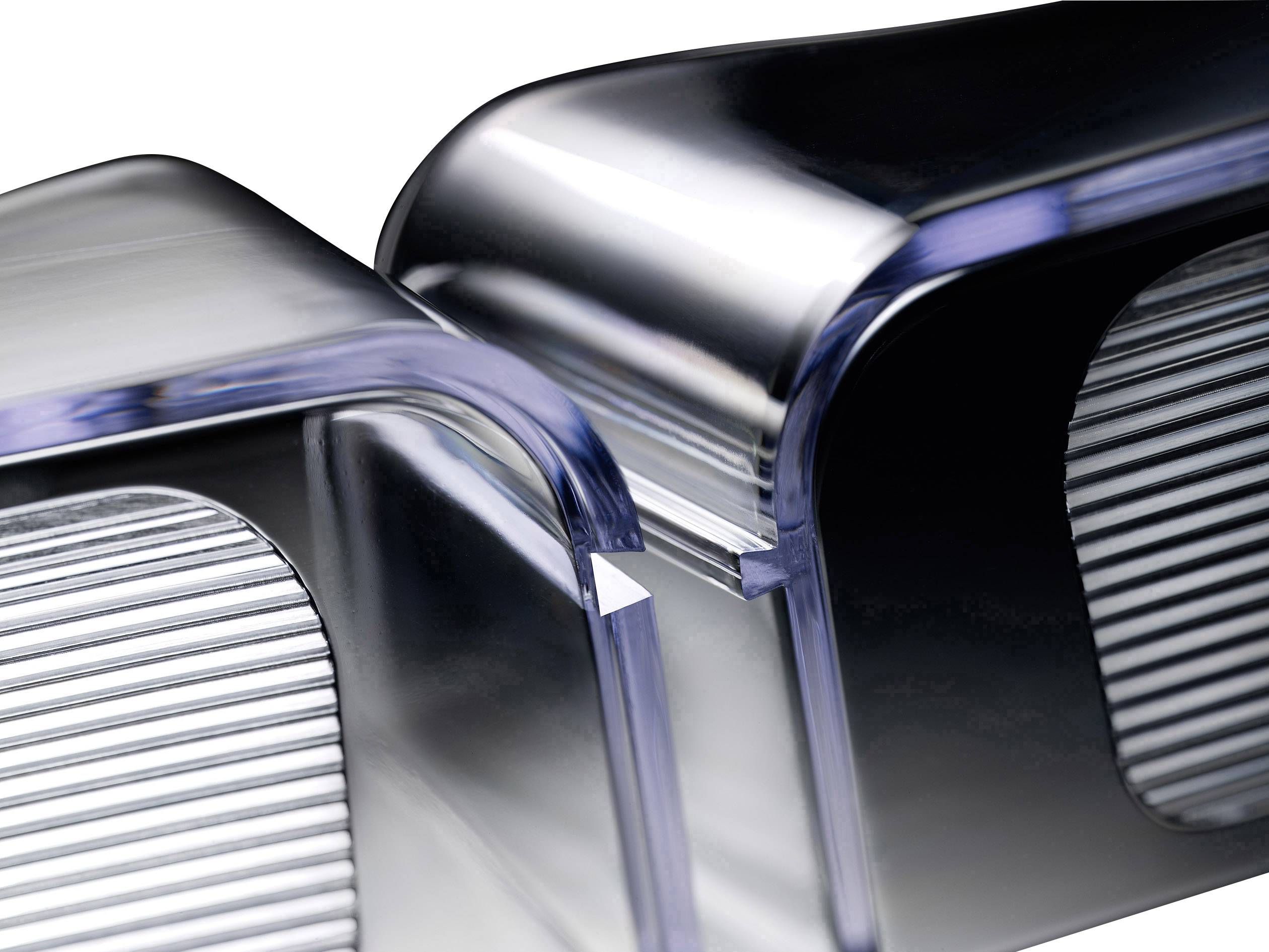 Close-up of two gleaming metal components with ribbed surfaces being joined at a precise point.