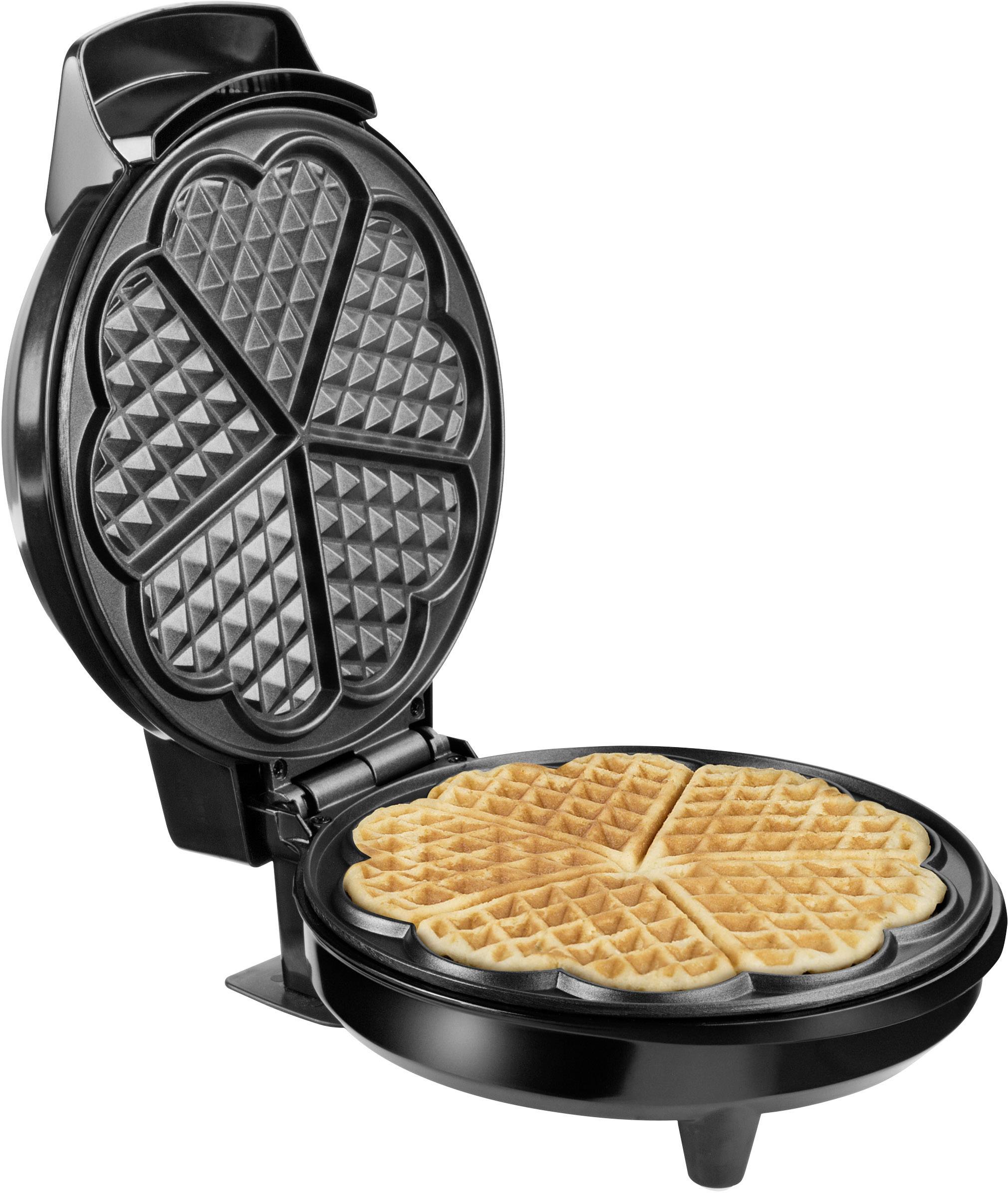 An open waffle iron with a freshly baked, heart-shaped waffle inside.