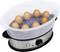 Steam cooker with eight brown eggs in a transparent steam container on a silver base.