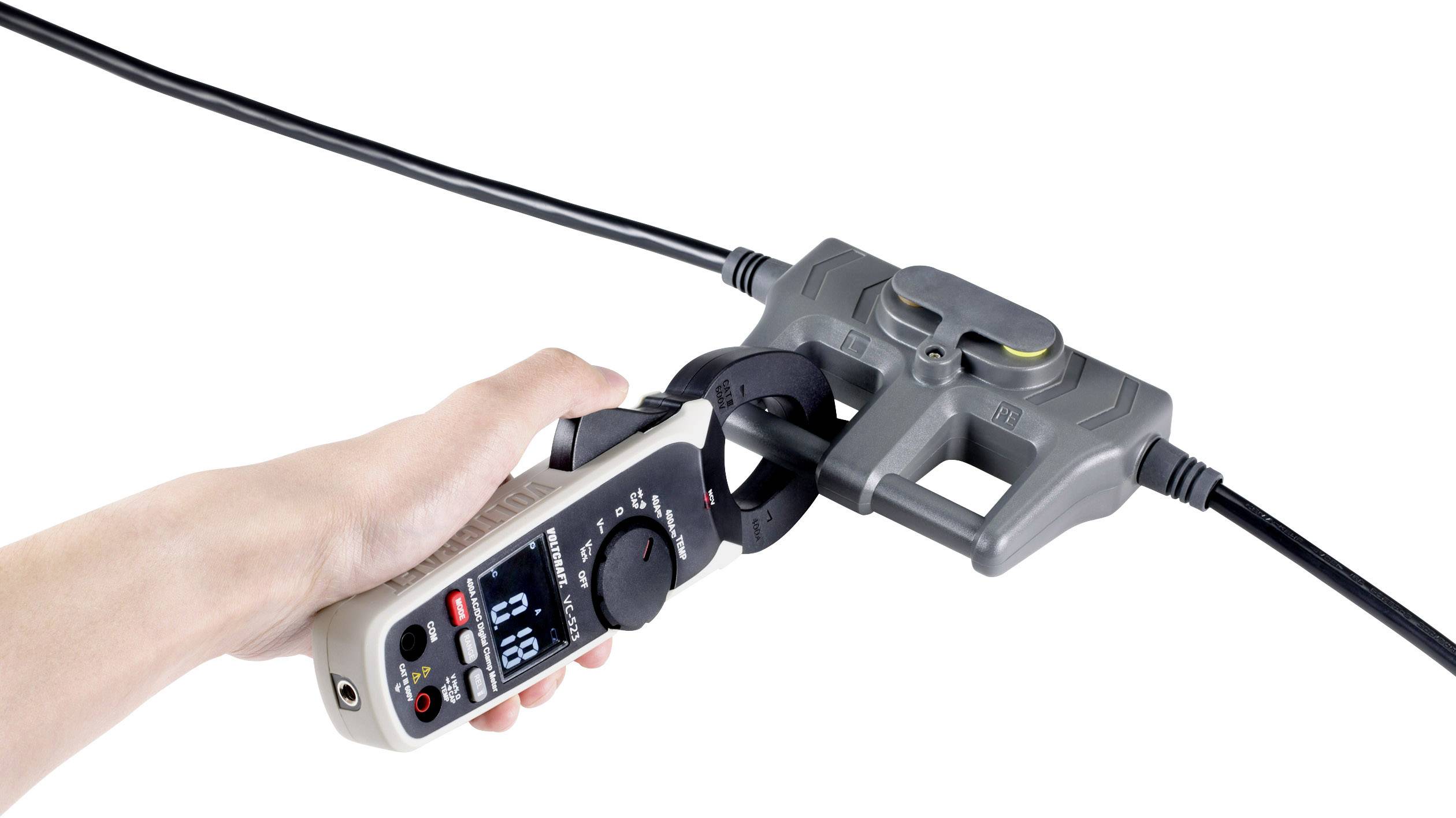 A hand is holding an electrical measuring device connected to a thick cable to measure current or voltage.