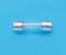 A small, transparent glass fuse with metal end caps on a blue background.