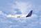 A Lufthansa Airbus A320 aircraft flies against a blue sky with clouds.