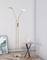 Floor lamp with two illuminating heads stands in a corner next to a small table with a vase. Artwork leans against the wall.