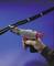 A hand is holding a tool to tighten cable ties around black cables. The tool has a red handle and attachments.