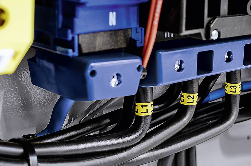 Close-up of electrical cables in a control cabinet with labels 'L1', 'L2', 'L3'. Each cable is connected to terminal clamps.