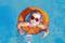 A small child wearing red sunglasses is swimming happily in an orange inflatable ring in the blue pool water. The temperature display shows 28.3°C.