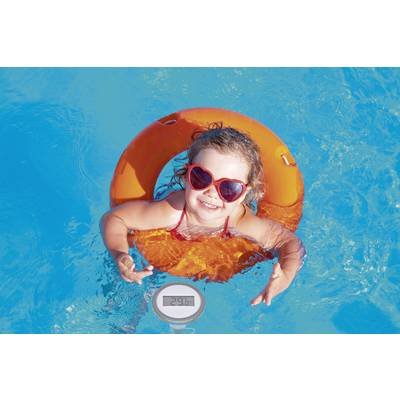 A smiling little girl with heart-shaped sunglasses swims in the blue pool on an orange rubber ring.