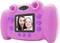 Pink children's camera with screen shows two smiling people. Buttons for recording and navigation are visible.
