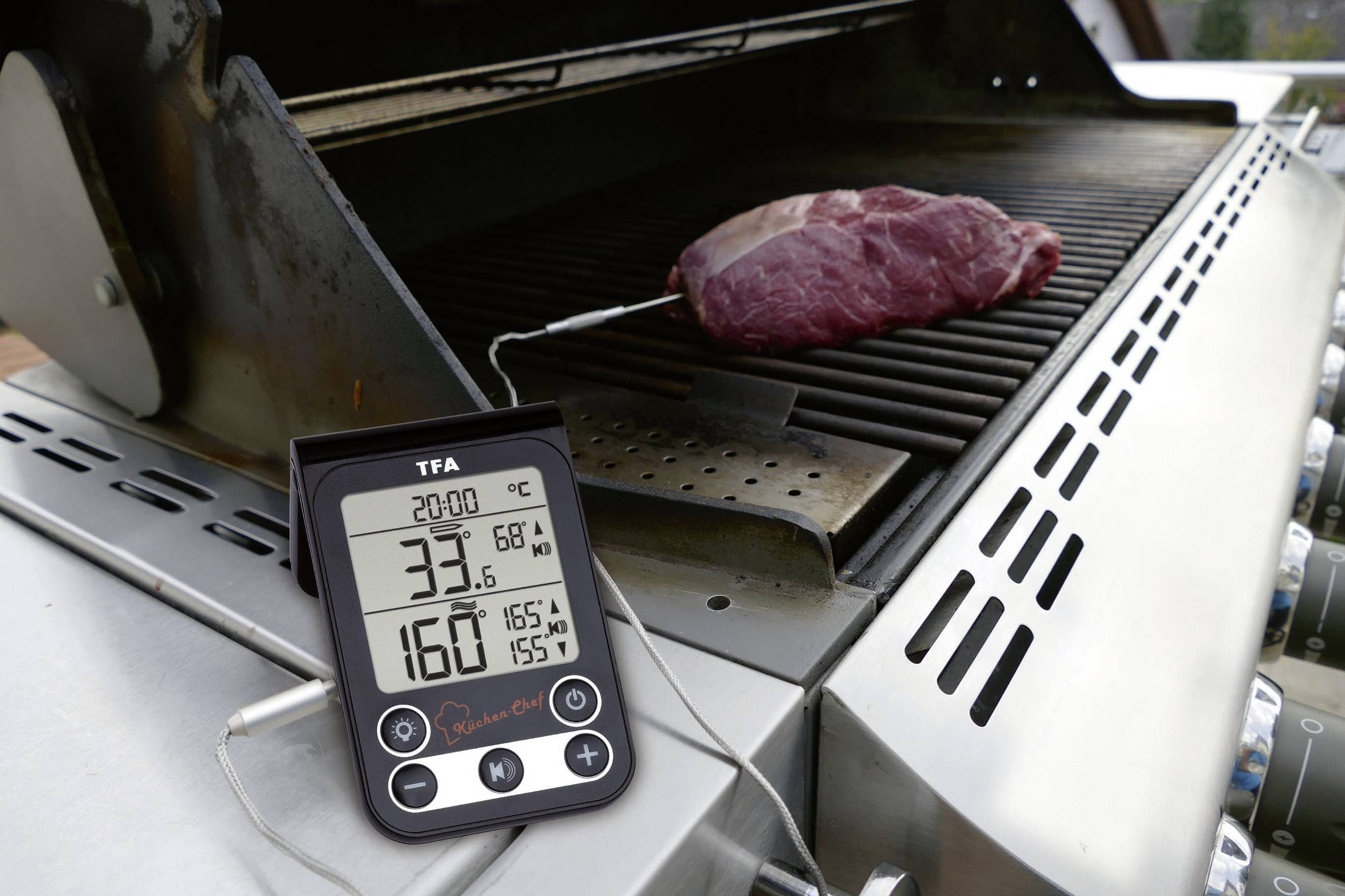 Digital grill thermometer display shows 33.6°C and target temperature 68°C. Piece of meat on the grill connected to the temperature probe.