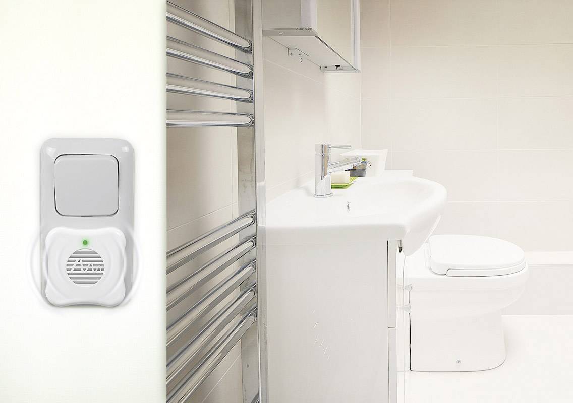 A modern bathroom with a washbasin, a towel radiator and a toilet. A light switch is visible on the left.