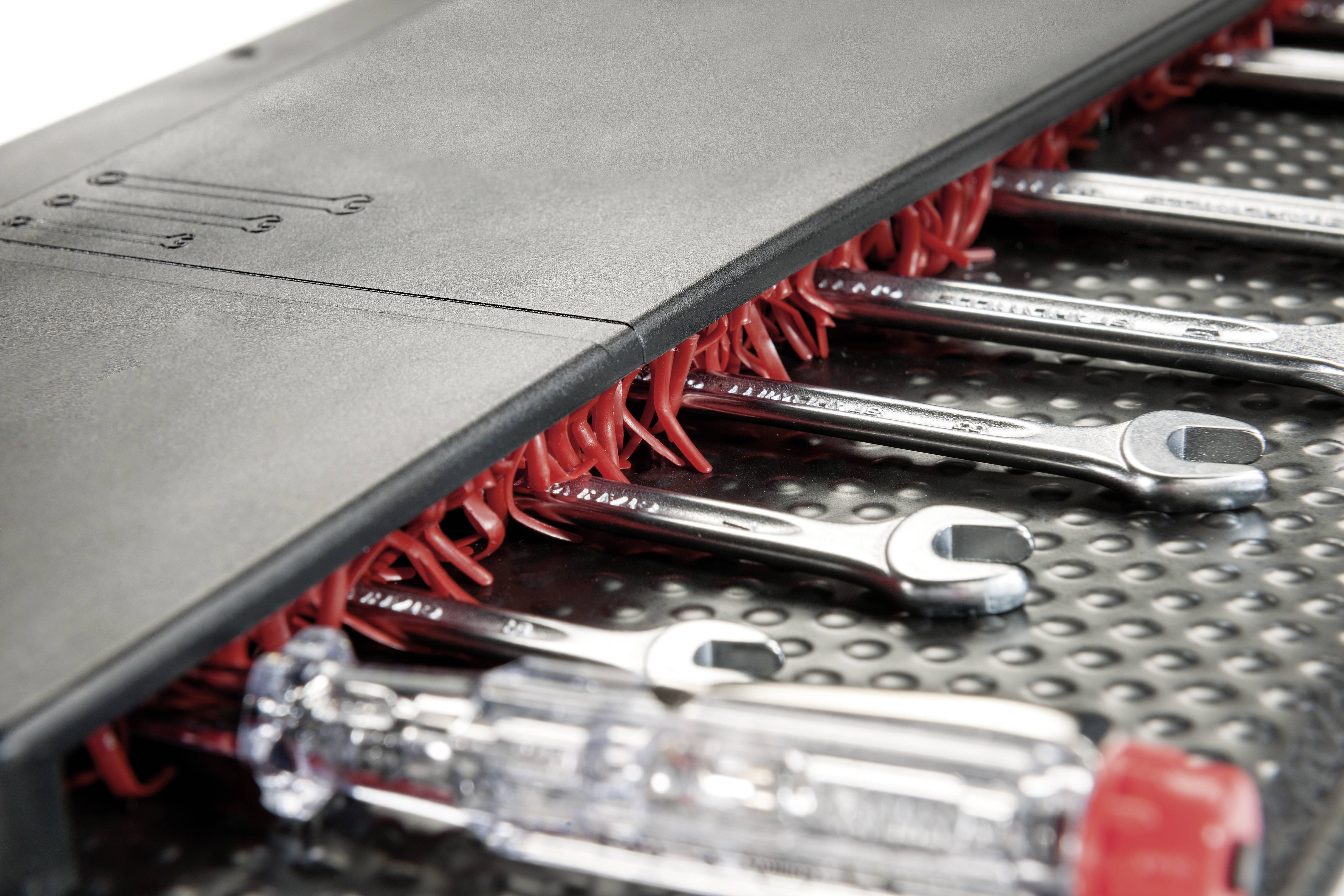 A set of spanners and a screwdriver in a holder on a metal sheet.