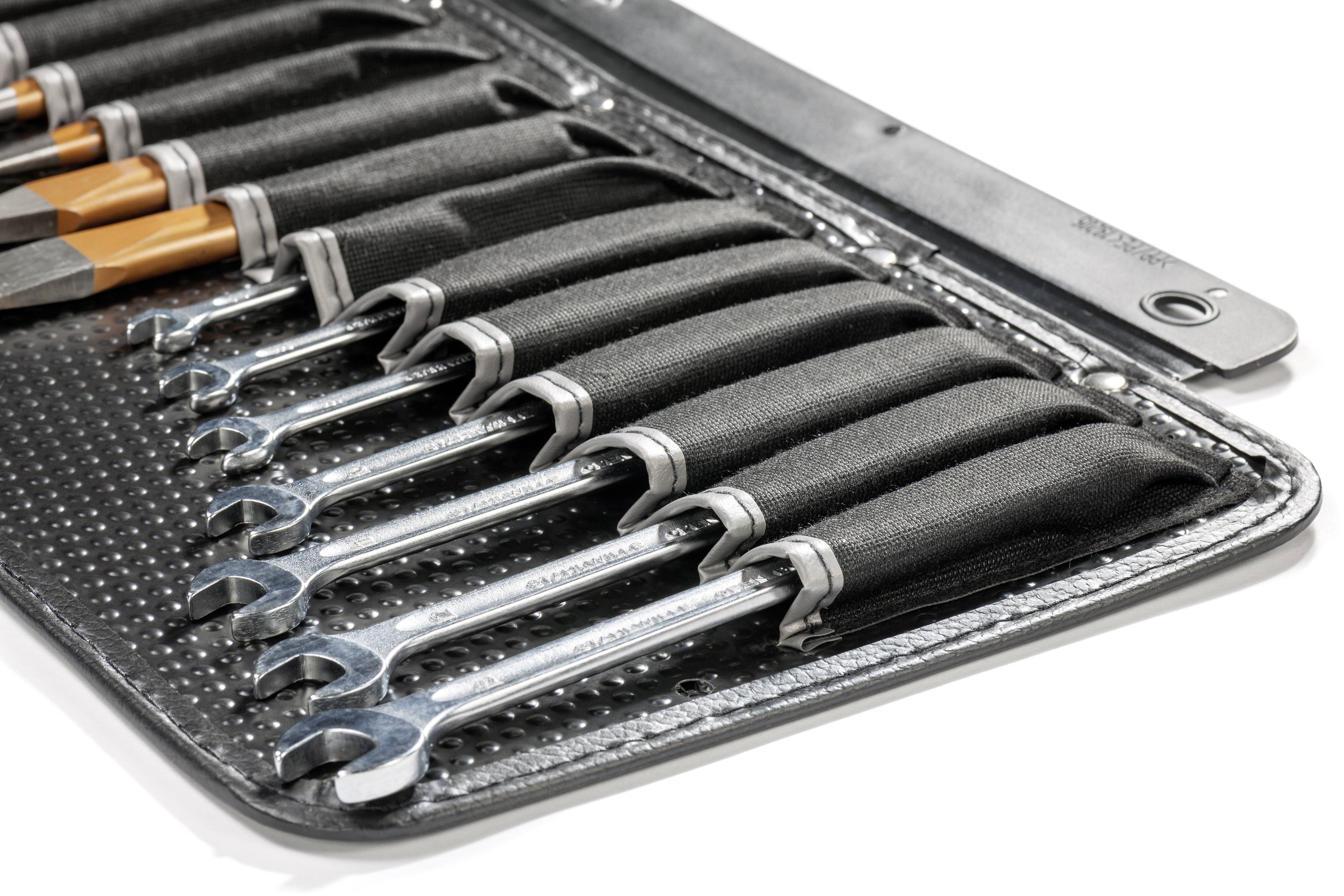 A set of open ring spanners in a rolled-up tool pouch. The spanners are secured in loops, designed for various screw sizes.