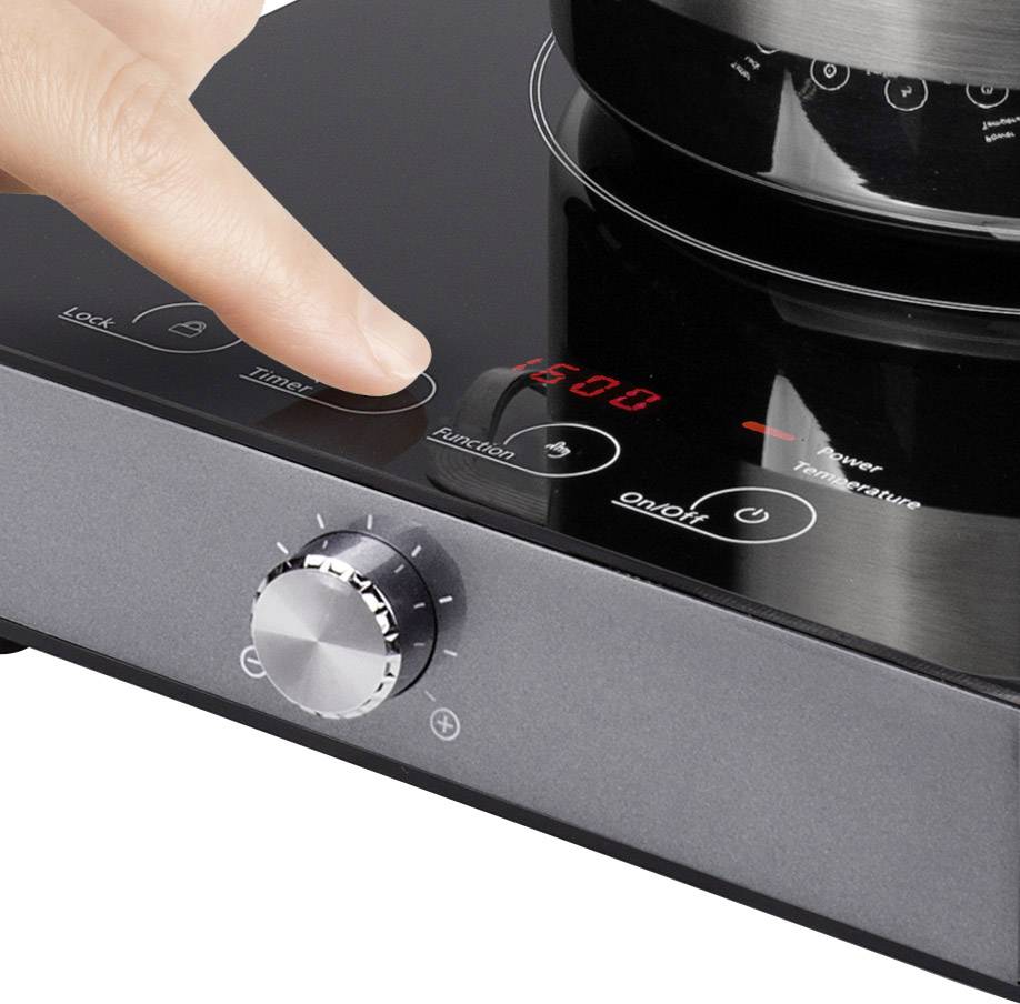 A hand is operating a hob with a digital display. The display shows '1500'. A rotary knob and additional buttons are visible.