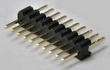 A golden pin header connector with multiple pins, lying on a grey surface. Suitable for electronic connections.