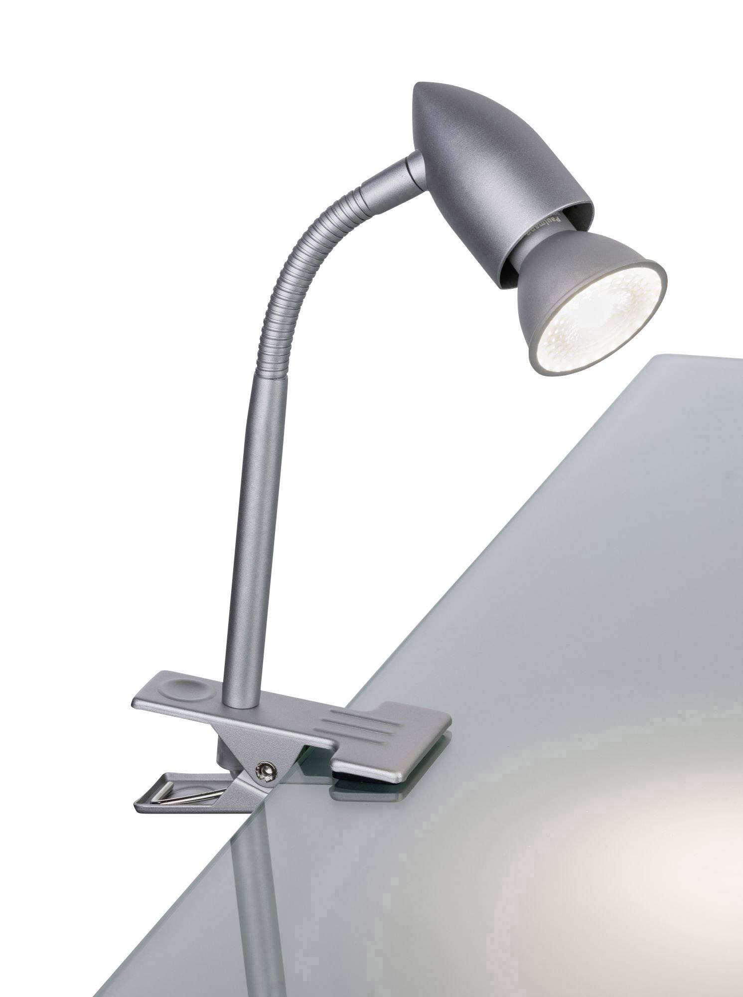 Metal clip-on lamp, attached to the edge of a glass table, with a flexible neck and a conical lampshade, emitting downward-directed light.