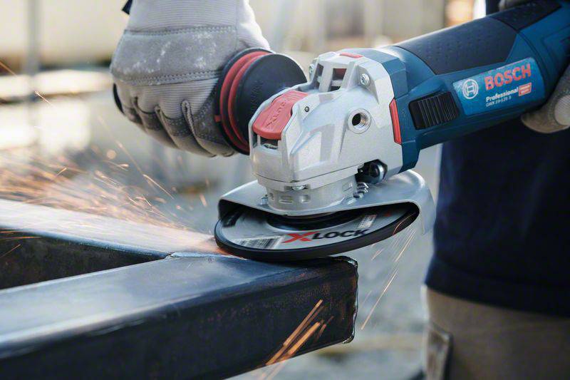 A hand holds an angle grinder, generating sparks while grinding a metal edge. The angle grinder is a Bosch brand.