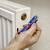 A hand is bleeding a radiator with a bleed valve key. The radiator is wall-mounted and white-painted.