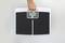A hand is lifting a digital personal weighing scale with a small display in the centre.