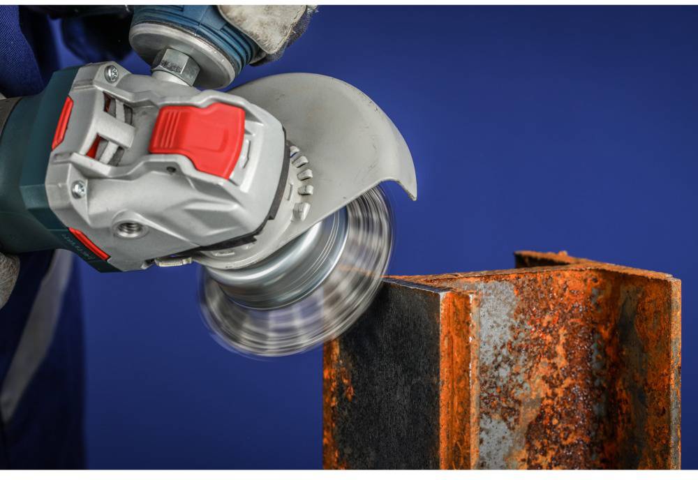 A grinding machine is used to remove rust from a metallic object. Sparks fly due to the friction.