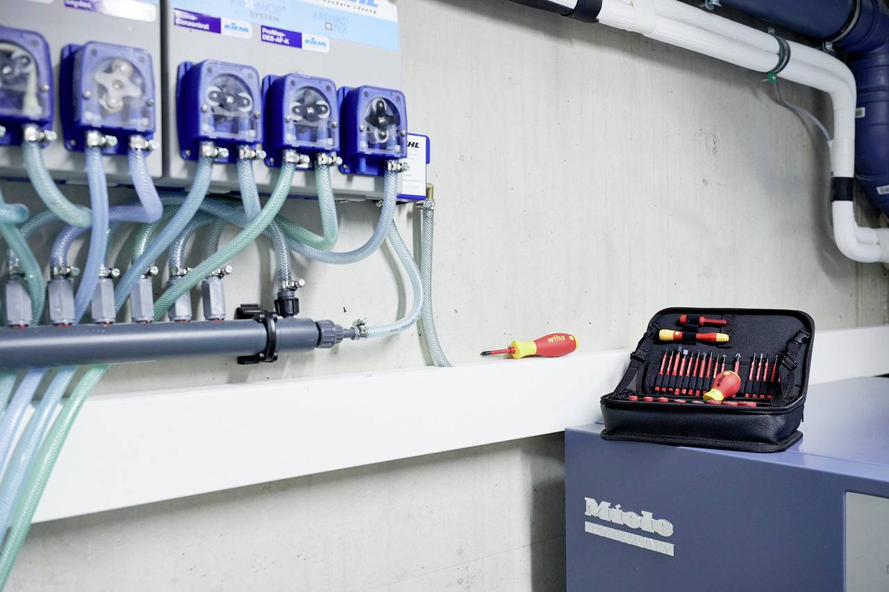 Technical installation on a wall with multiple tubes and connections. An open tool set lies on a box.