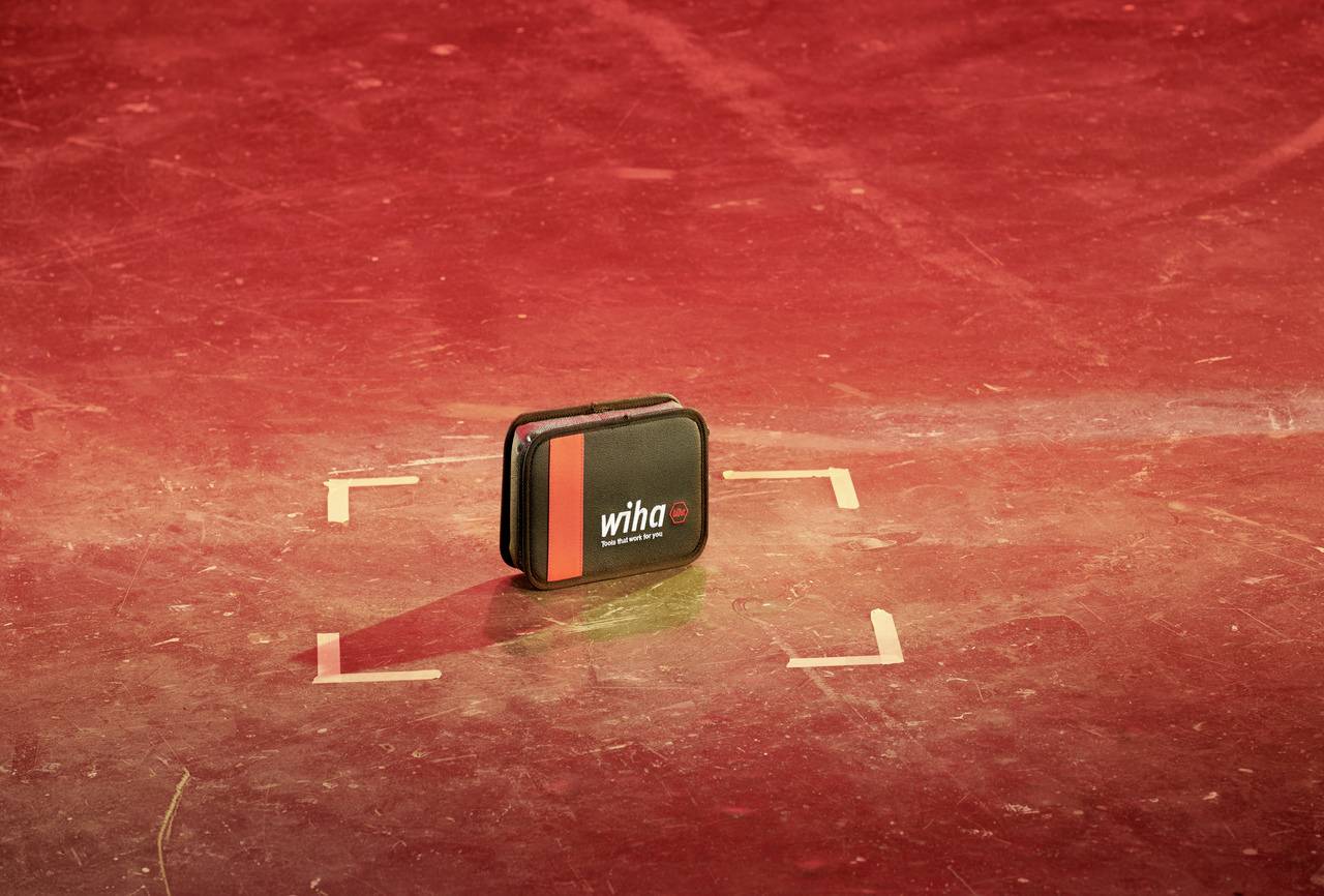 Small black tool case by 'Wiha' brand on a red background, positioned centrally.