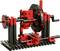 A small machine model made of red and black building blocks with gears and axles, representing a mechanical device.