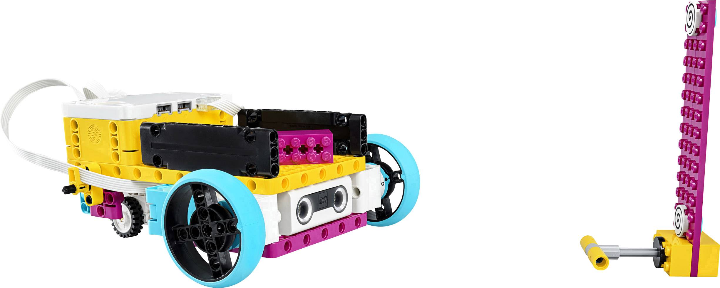 A colourful LEGO vehicle with wheels and sensors in front of a simple construction made of LEGO bricks.